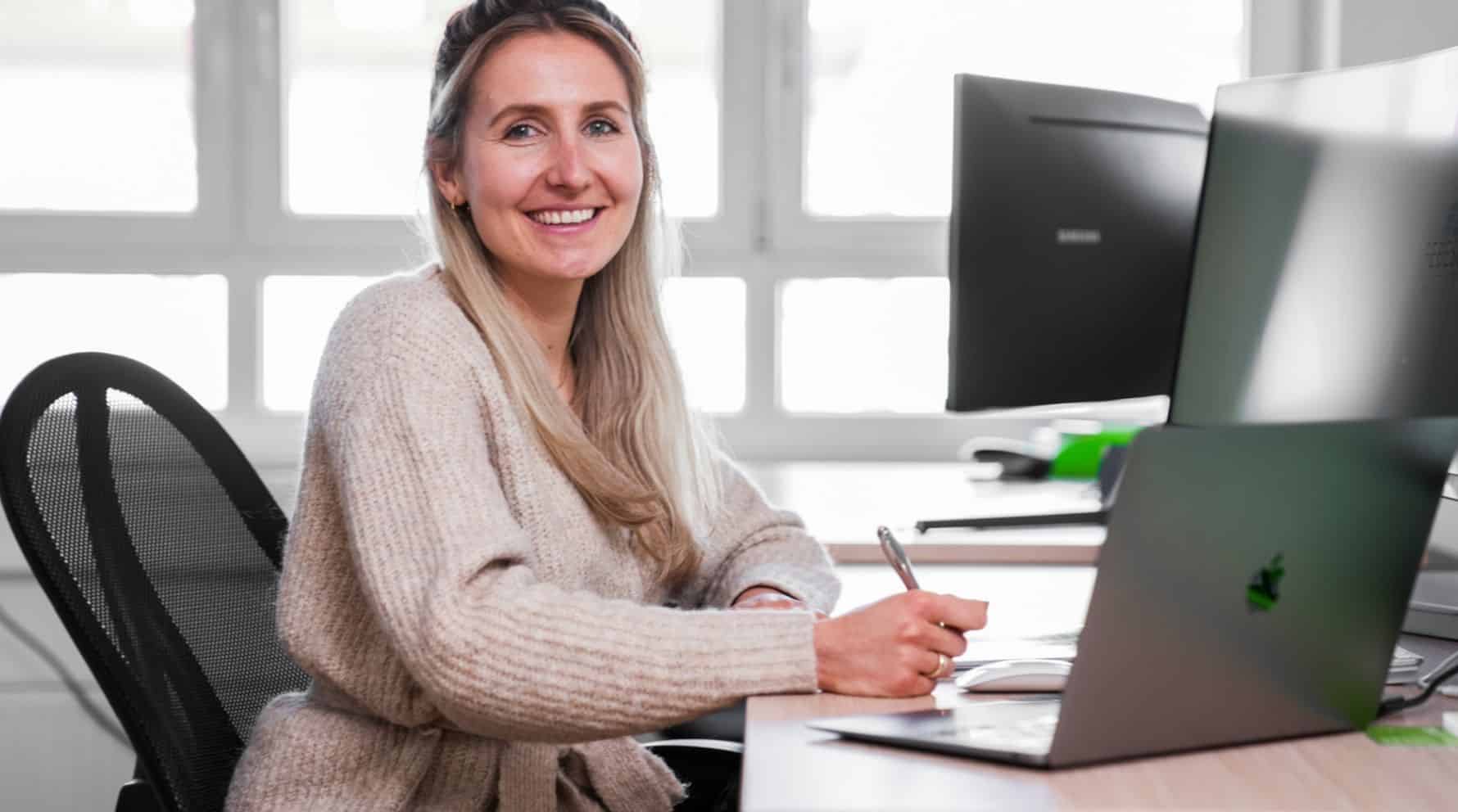 FEBESOL-Mitarbeiterin sitzt vor einem Laptop mit einem Stift in der Hand