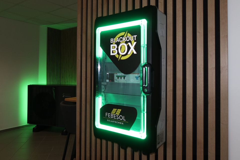 Beleuchteter Verkaufsautomat mit der Aufschrift „Blackout Box“ vor einer Holzlattenwand mit grüner Umgebungsbeleuchtung.