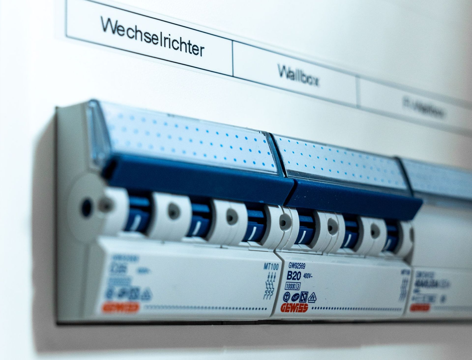 Nahaufnahme eines modernen elektrischen Sicherungskastens mit beschrifteten Schaltern, darunter „Wechselrichter“ und „Wallbox“, Teil der Initiative KFW-Förderprogramm 442.