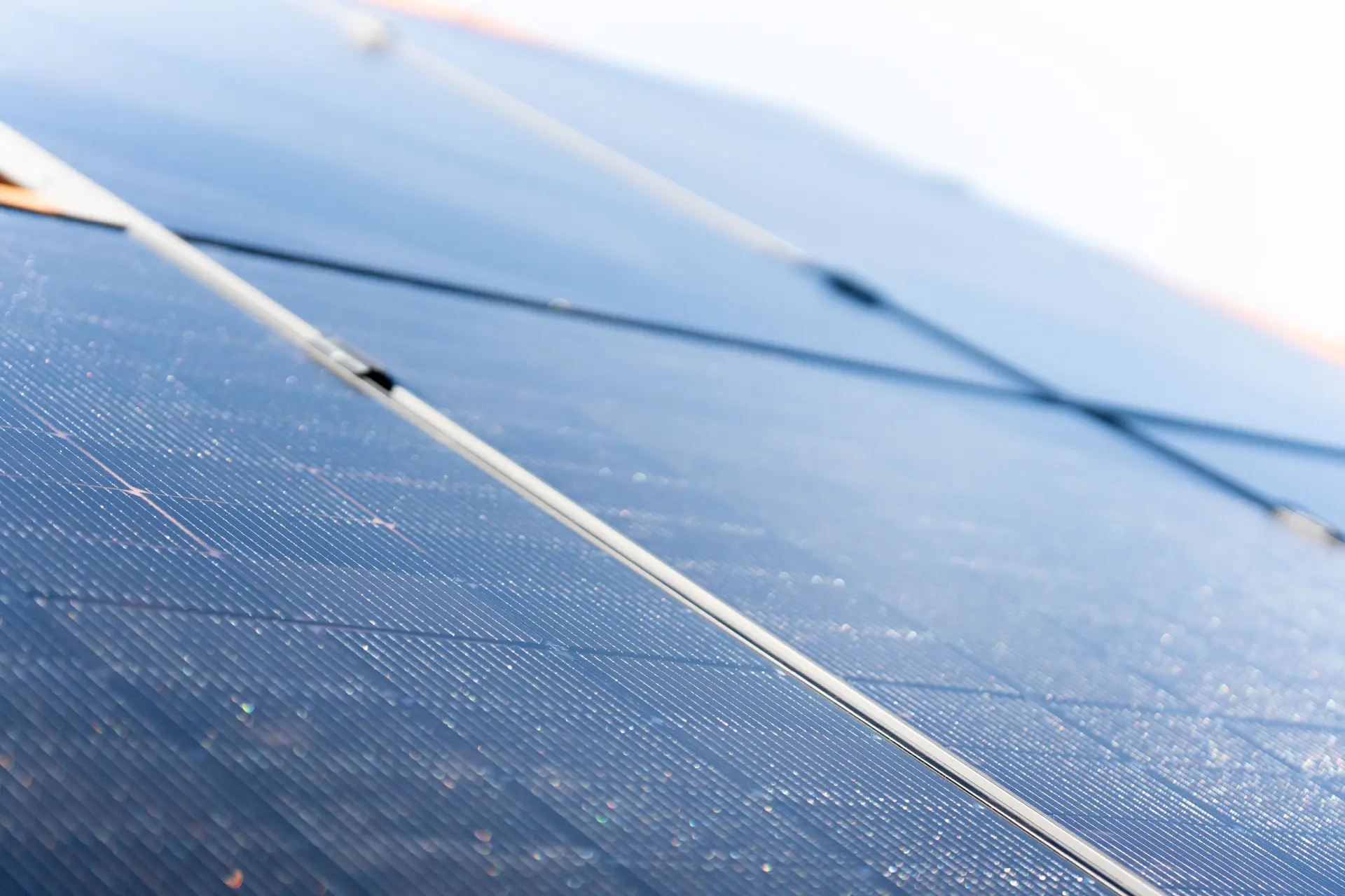 Nahaufnahme von abgewinkelten Solarmodulen, die das Sonnenlicht reflektieren, mit einem hellen Himmel im Hintergrund, Teil einer 10 kWp PV-Anlage mit Speicher.