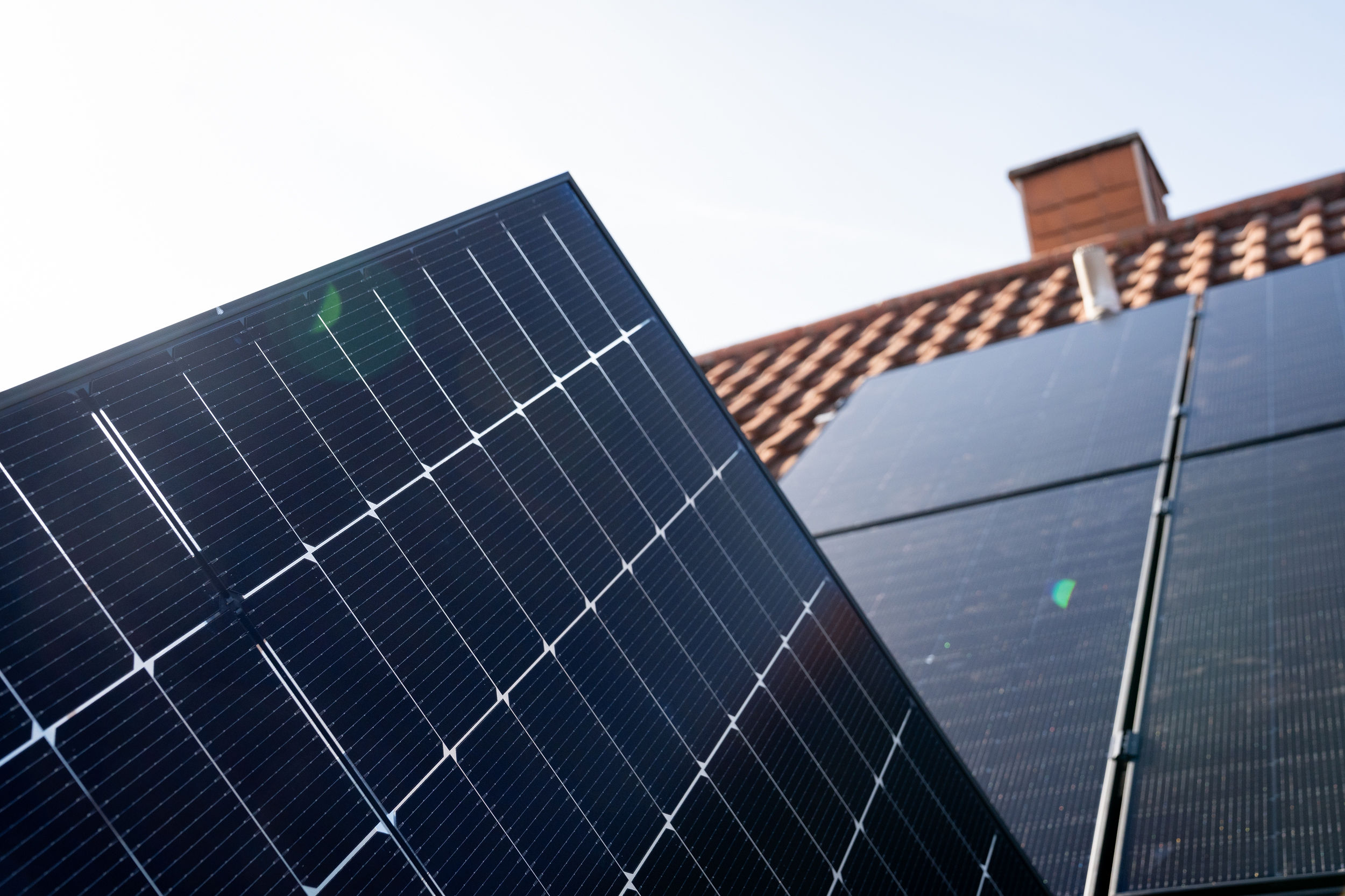 Nahaufnahme der Solarpaket 1-Module, die auf einem roten Ziegeldach unter einem klaren blauen Himmel installiert sind.