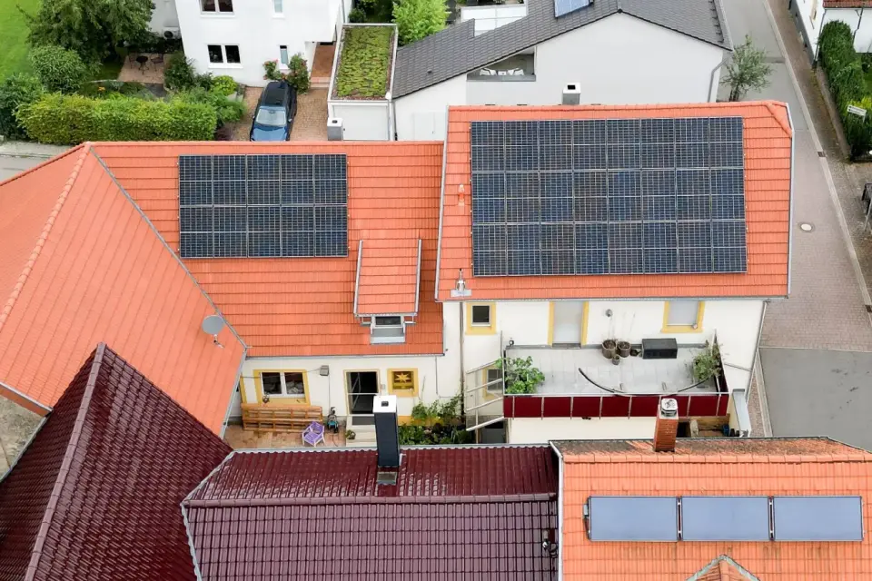 Luftaufnahme von Häusern mit Sonnenkollektoren auf orangefarbenen Dächern in einem Vorortviertel.