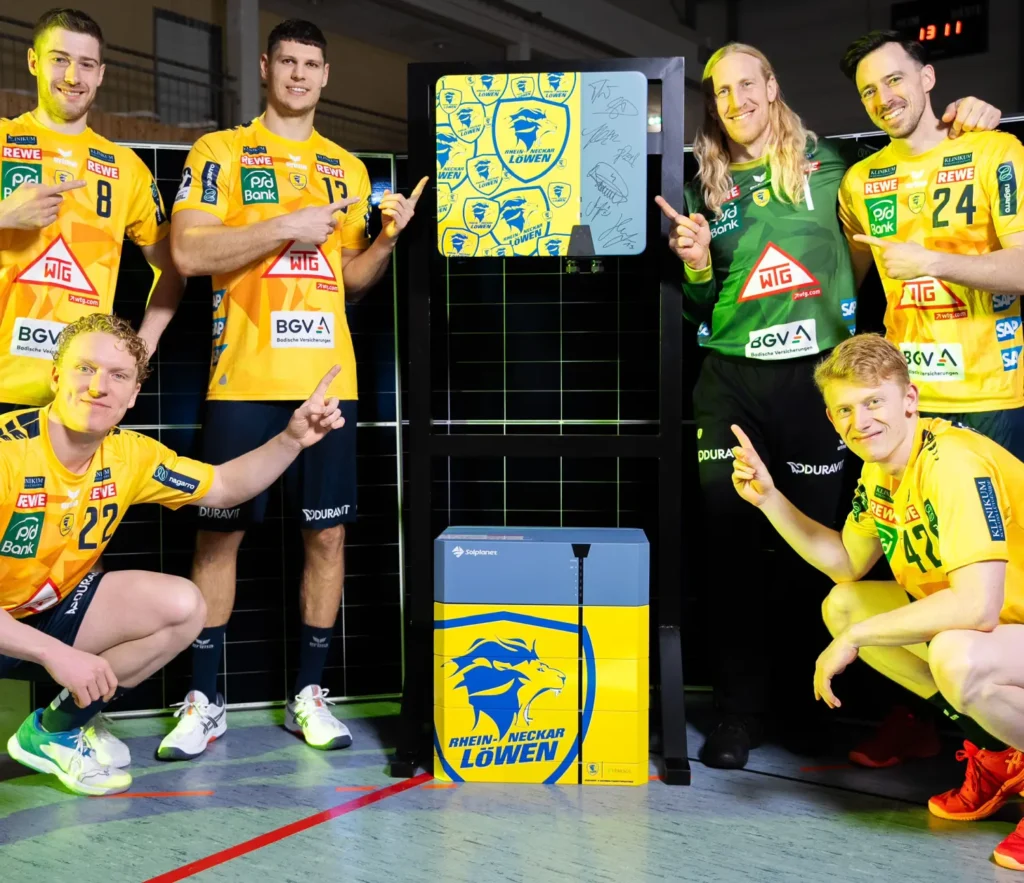 Eine Gruppe von fünf Handballspielern in gelben Trikots posiert um ein Display mit dem Logo der Rhein-Neckar Löwen.