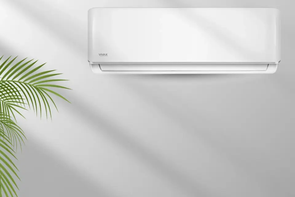 Weiße Wandklimaanlage mit einer grünen Pflanze im Vordergrund.
